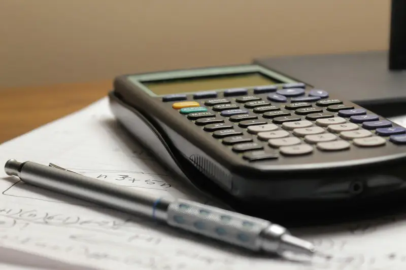 Calculadora e caneta sobre papéis de contas.